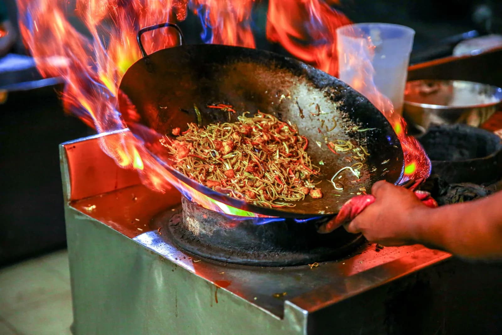 Noodles tossed in a wok over a roaring flame at a street stall