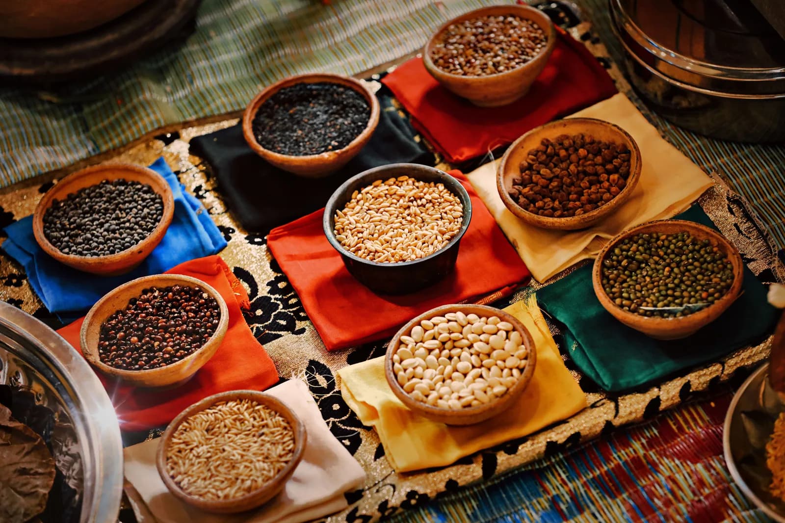Clay bowls of dried lentils, beans and grains set out on squares of bright cloth
