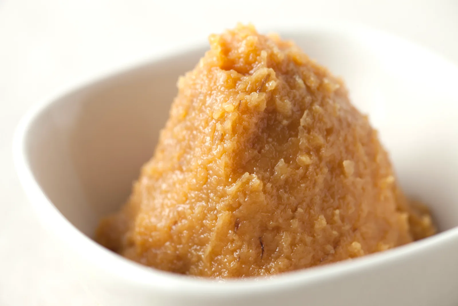 A mound of light brown miso paste in a white bowl