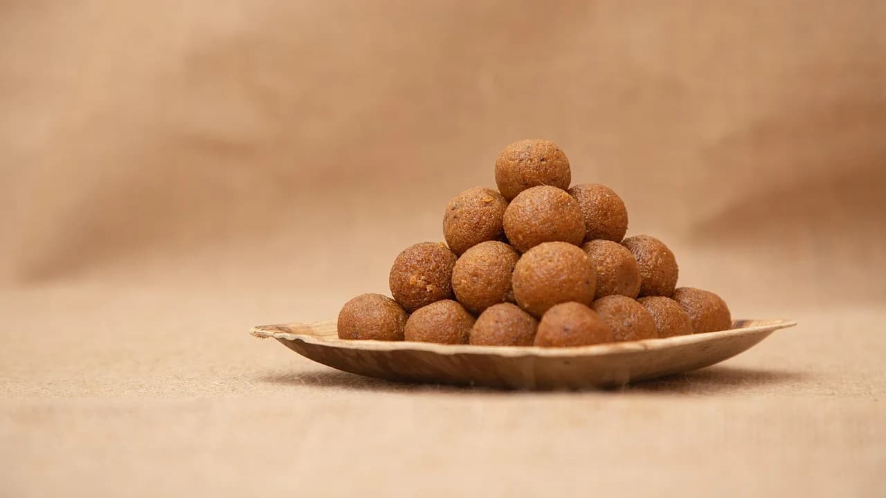 A pyramid of brown laddu on a leaf plate