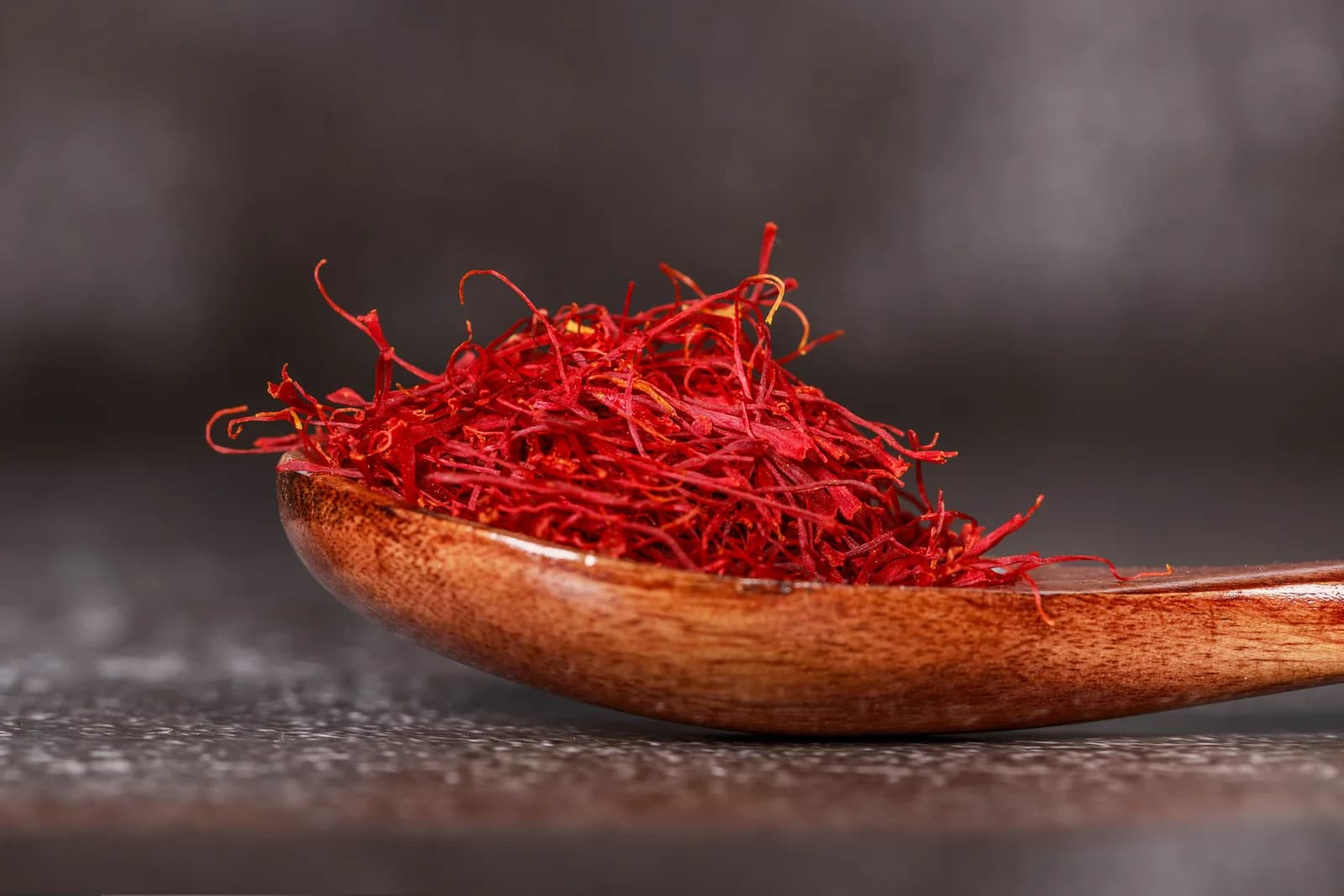 Dried saffron threads heaped on a wooden spoon
