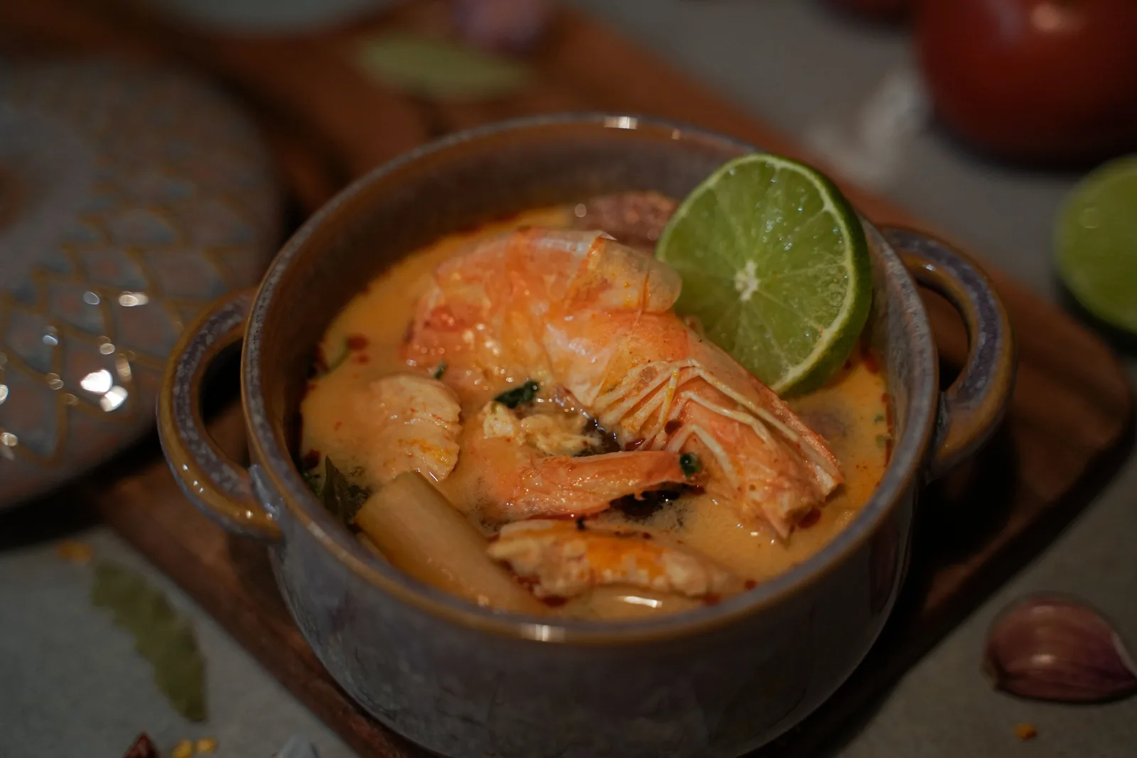 Tom yum with shrimp in a small clay pot, half a lime on top